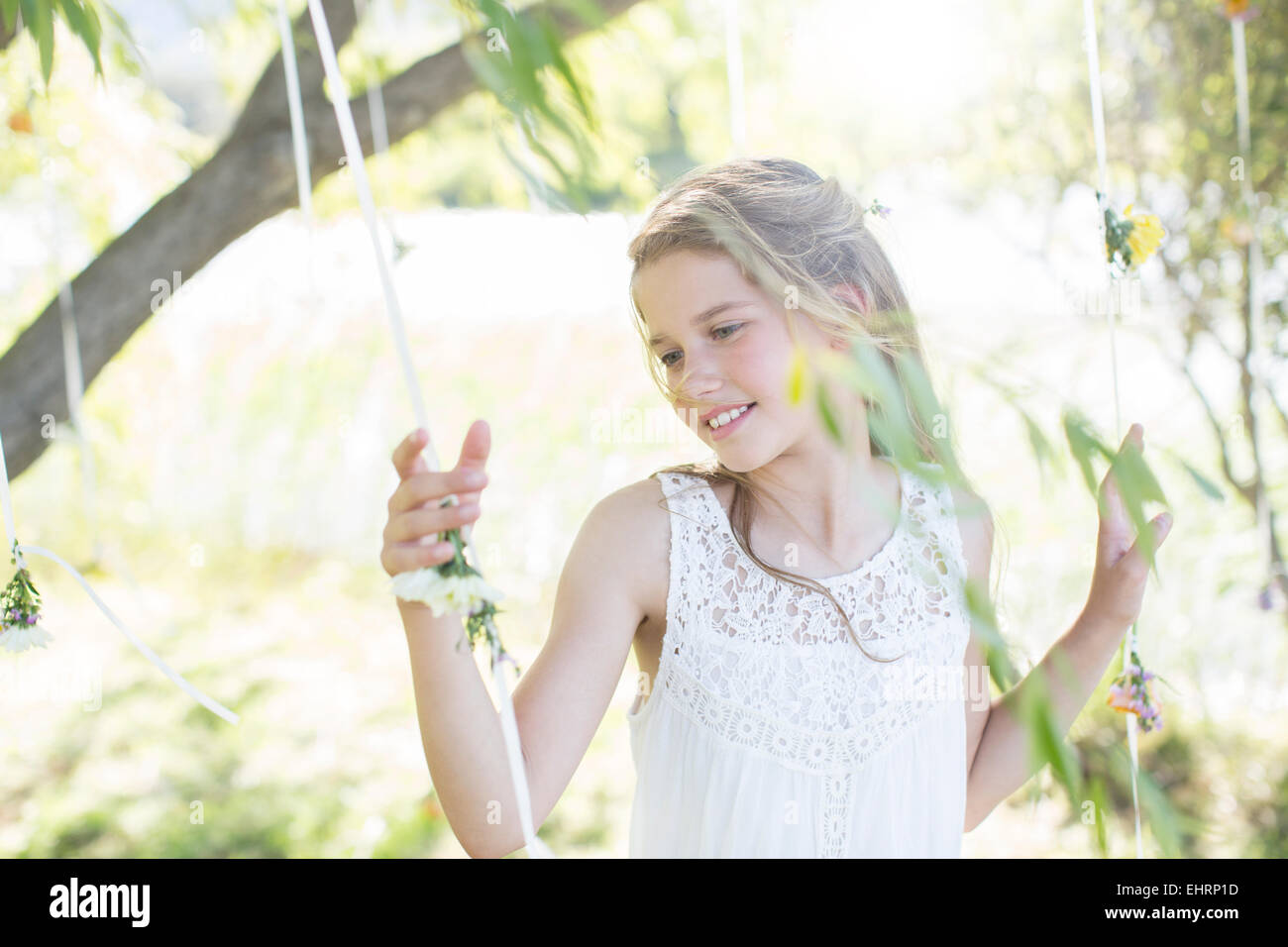 Sorridente damigella giocando con decorazioni in giardino interno durante il ricevimento di nozze Foto Stock