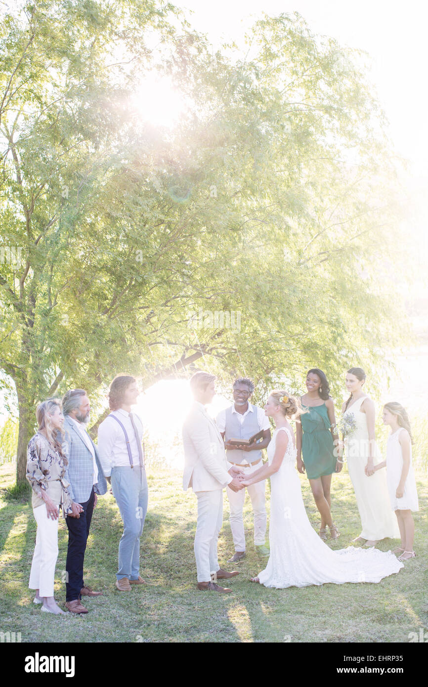 Coppia giovane e gli ospiti durante la cerimonia di matrimonio nel giardino interno Foto Stock