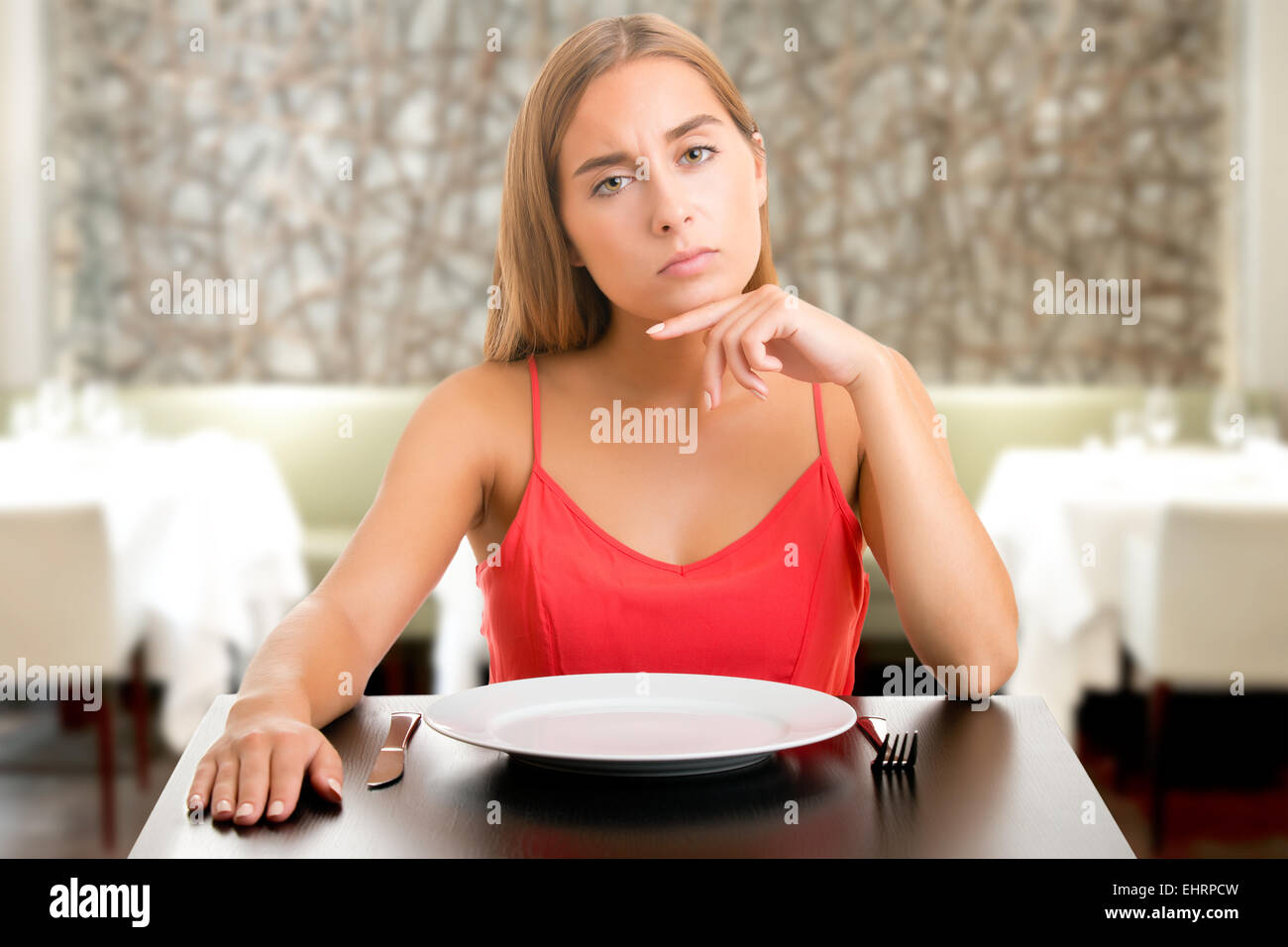 Fame donna su una dieta in attesa con un piatto vuoto in un ristorante Foto Stock