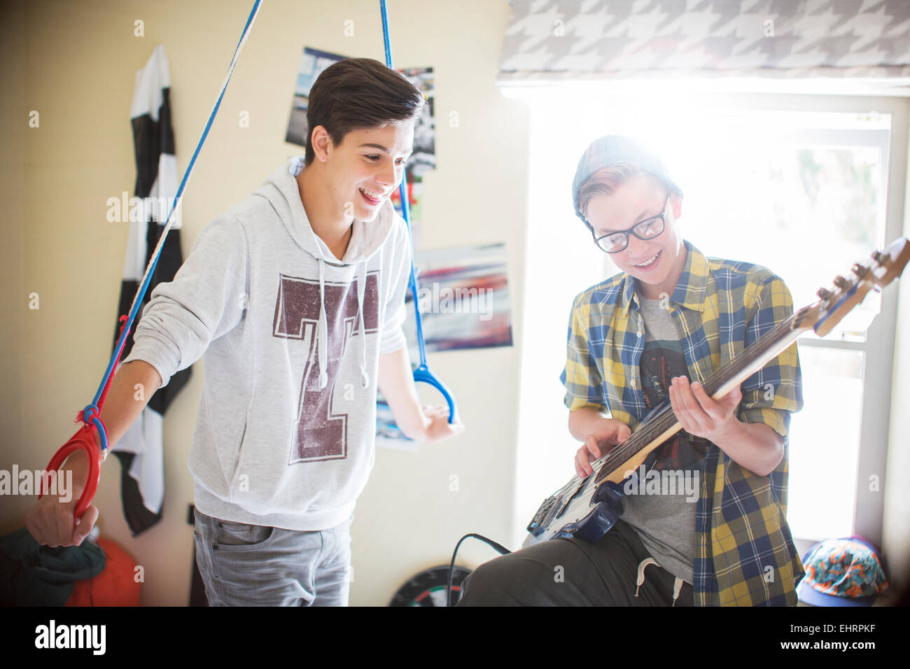Due ragazzi adolescenti divertendosi e suonare la chitarra elettrica in camera Foto Stock