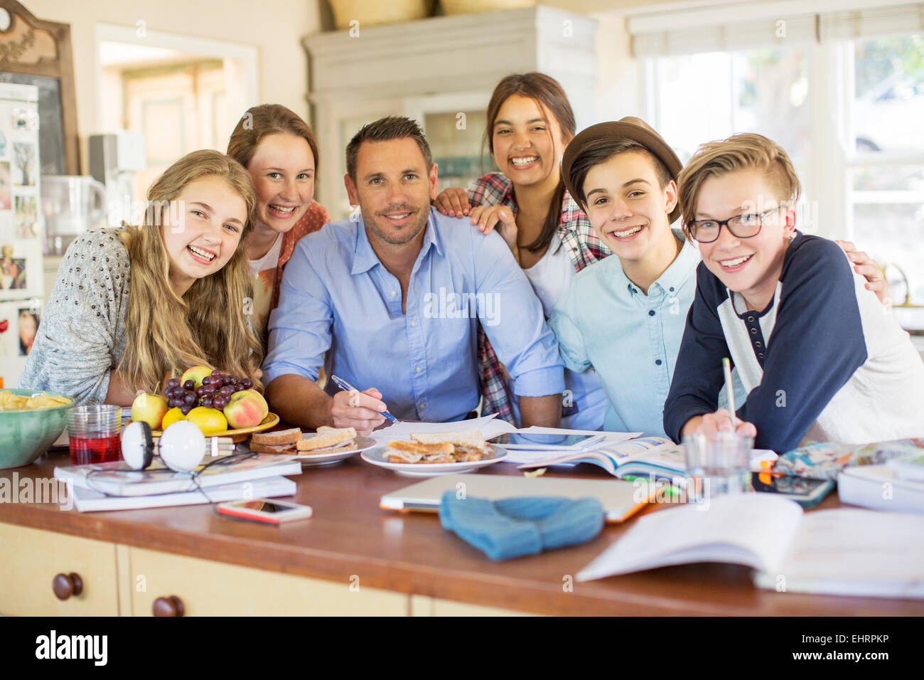 Gruppo di adolescenti con metà uomo adulto seduto al tavolo nella sala da pranzo Foto Stock
