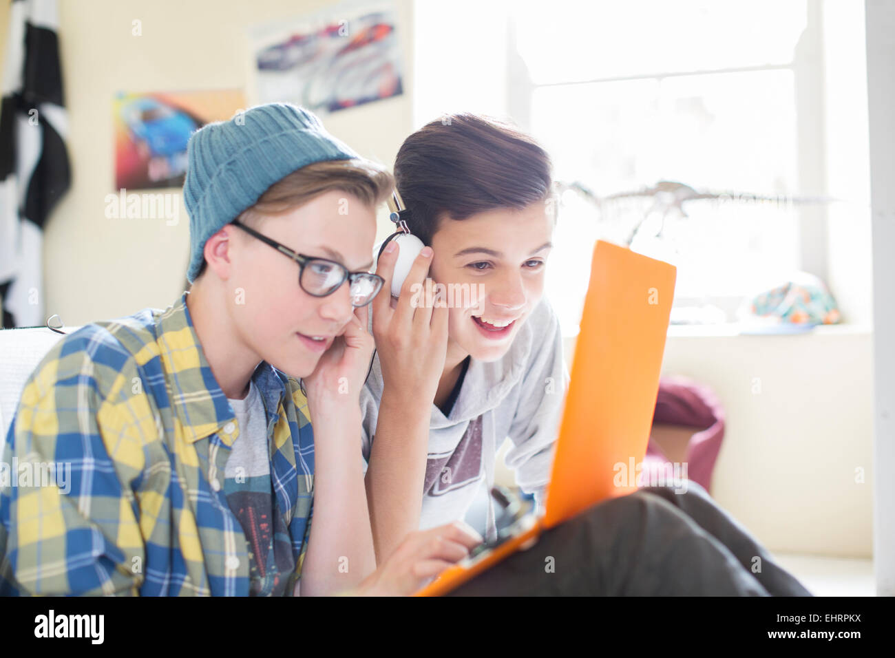 Due ragazzi adolescenti la condivisione di computer portatile e le cuffie in camera Foto Stock