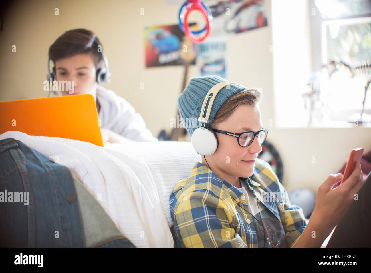 Due ragazzi adolescenti utilizzando dispositivi elettronici in camera Foto Stock