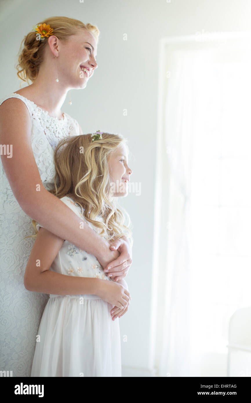 Sposa abbracciando damigella e guardando fuori della finestra Foto Stock