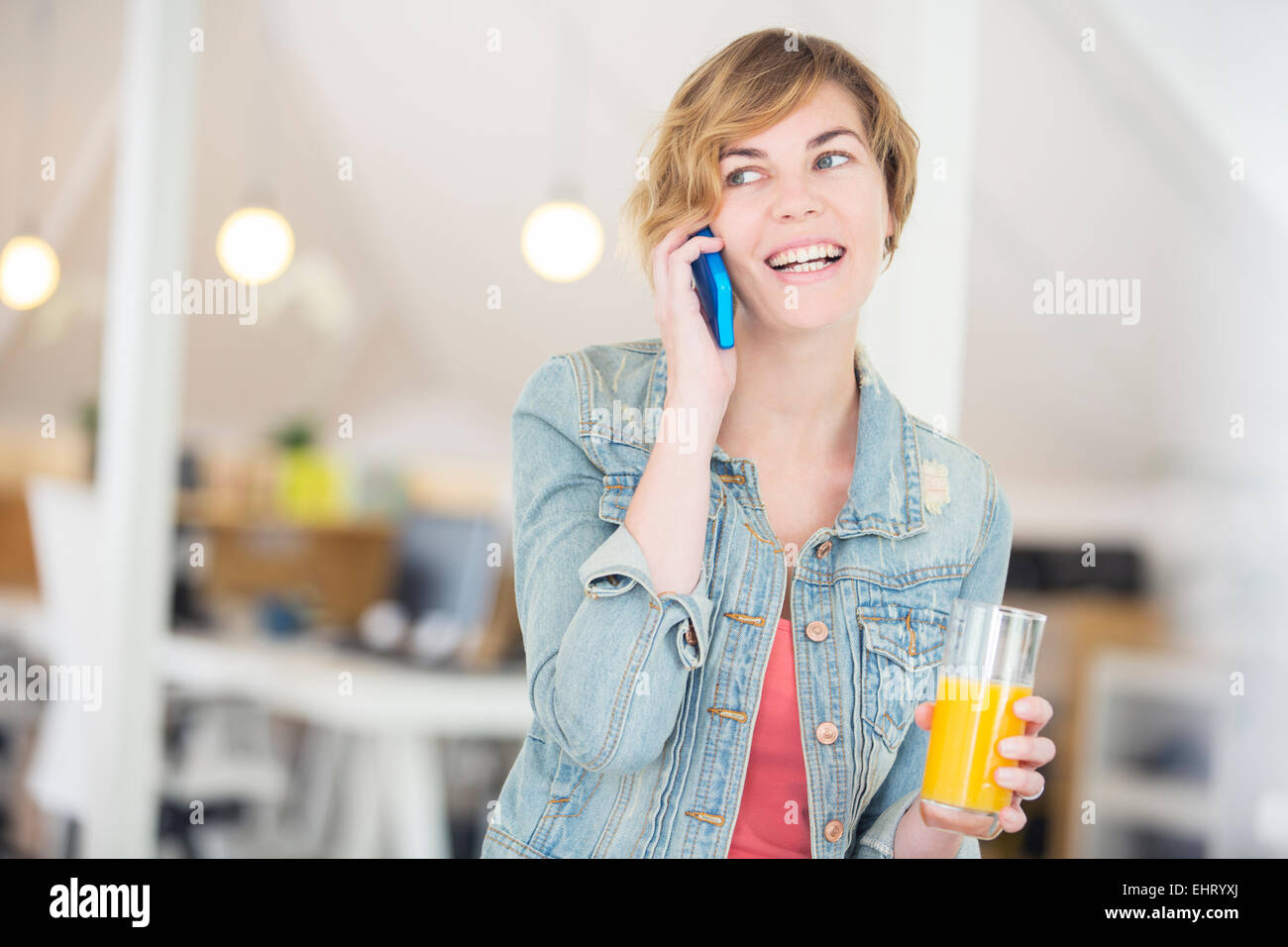 Lavoratore di ufficio parlando al telefono e tenendo un bicchiere di succo di frutta Foto Stock