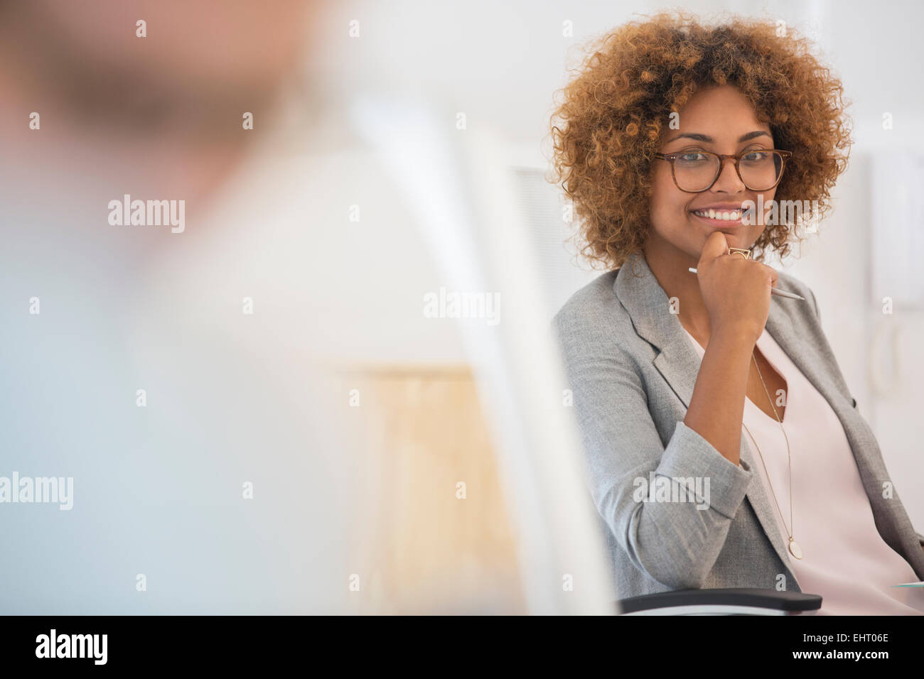 Ritratto di donna seduta in office,indossa occhiali e sorridente Foto Stock