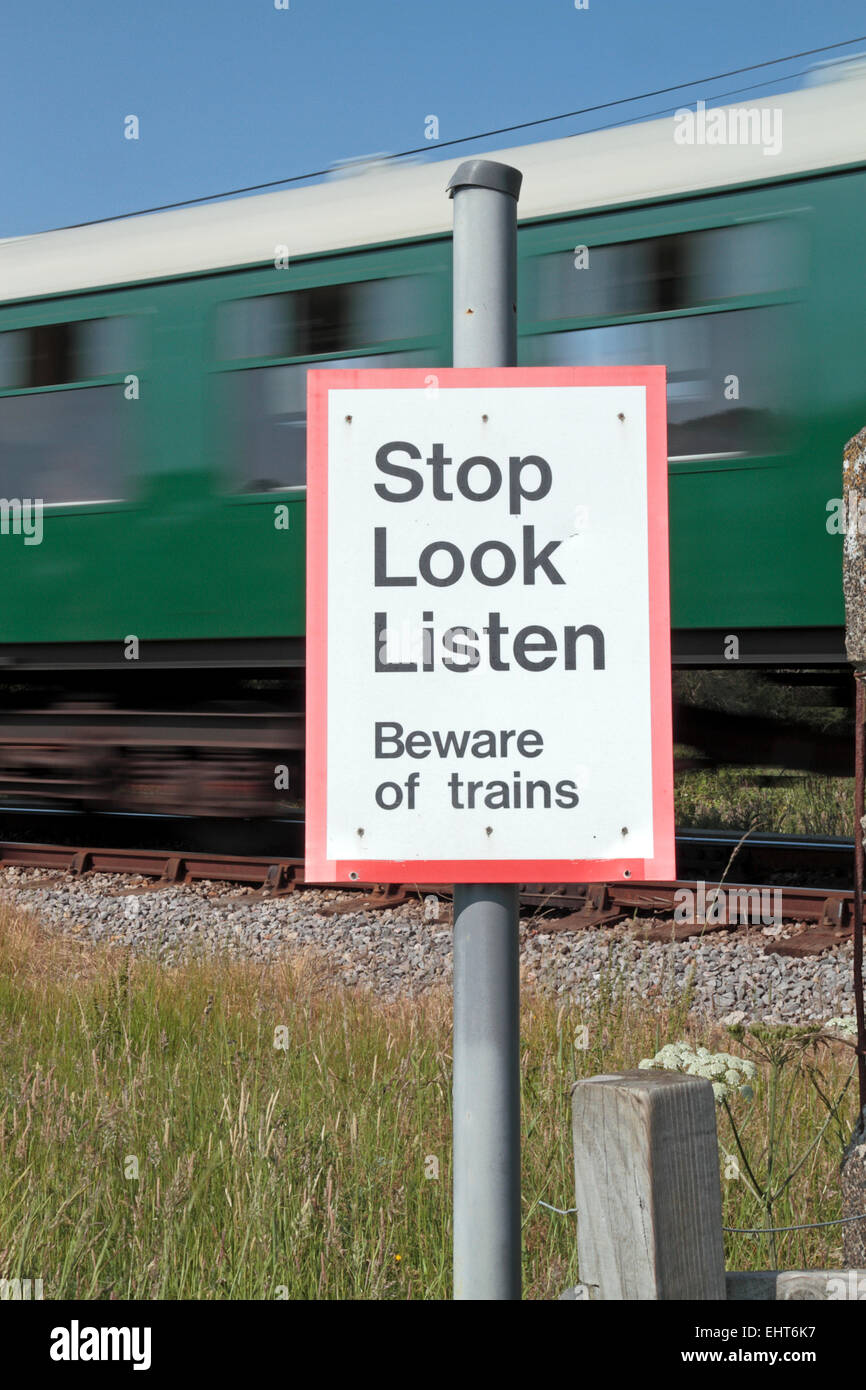 Un 'Stop guardare ascoltare attenti di treni' segno su un piede pubblica incrocio a Swanage linea ferroviaria nelle vicinanze Corfe Castle, Dorset, Regno Unito. Foto Stock