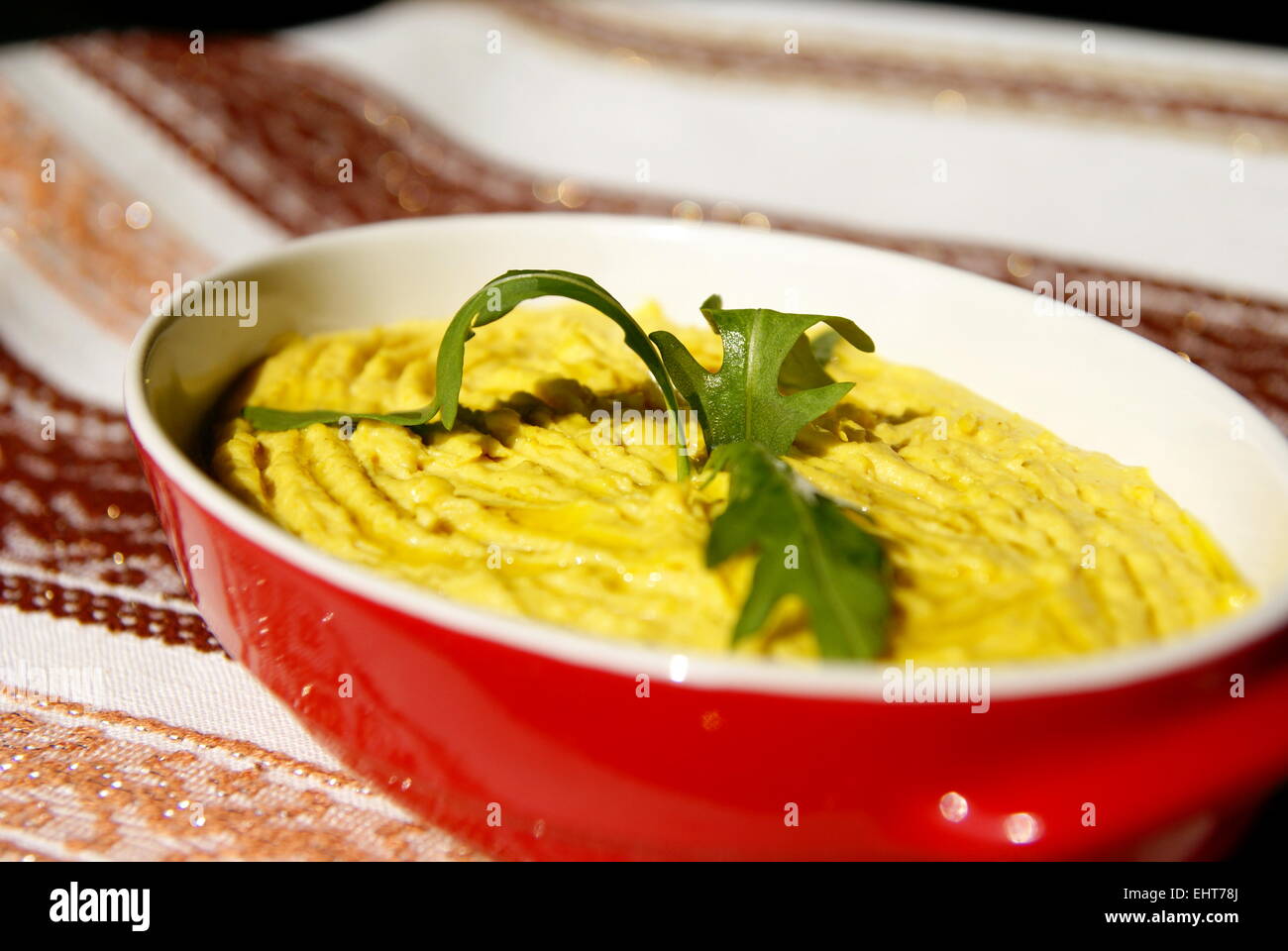 Humus pasta con olio e peperoncino, decorata con rucola Foto Stock