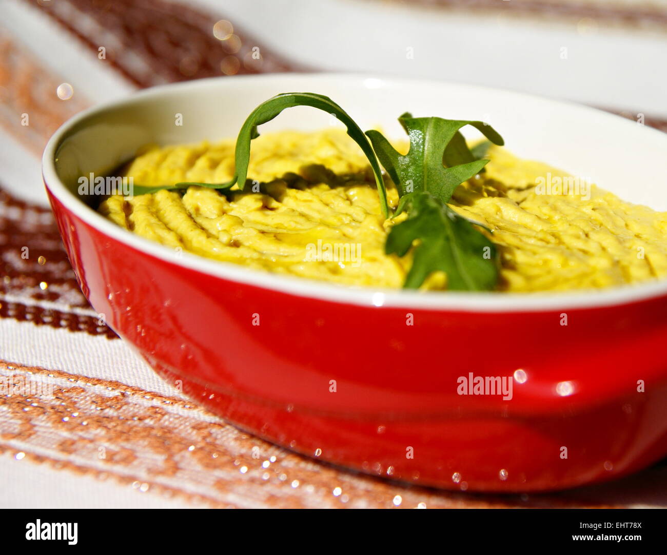 Humus pasta con olio e peperoncino, decorata con rucola Foto Stock