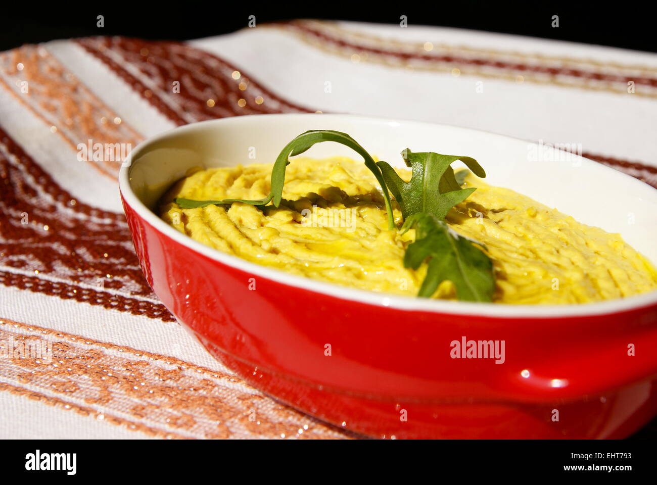 Humus pasta con olio e peperoncino, decorata con rucola Foto Stock