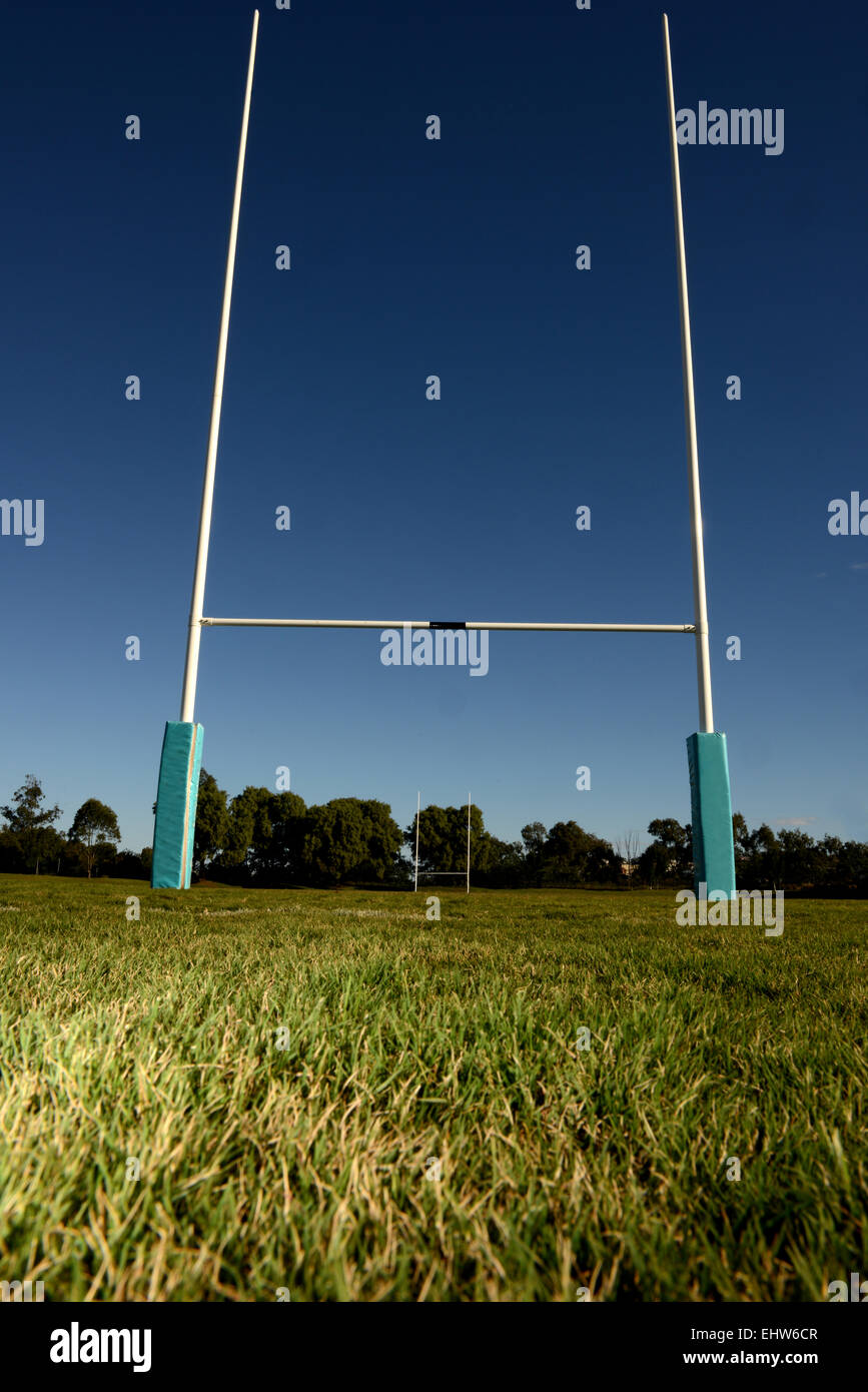 Basso angolo di visione di un set di rugby pali, impostare contro un cielo blu sullo sfondo, con erba verde in primo piano. Foto Stock