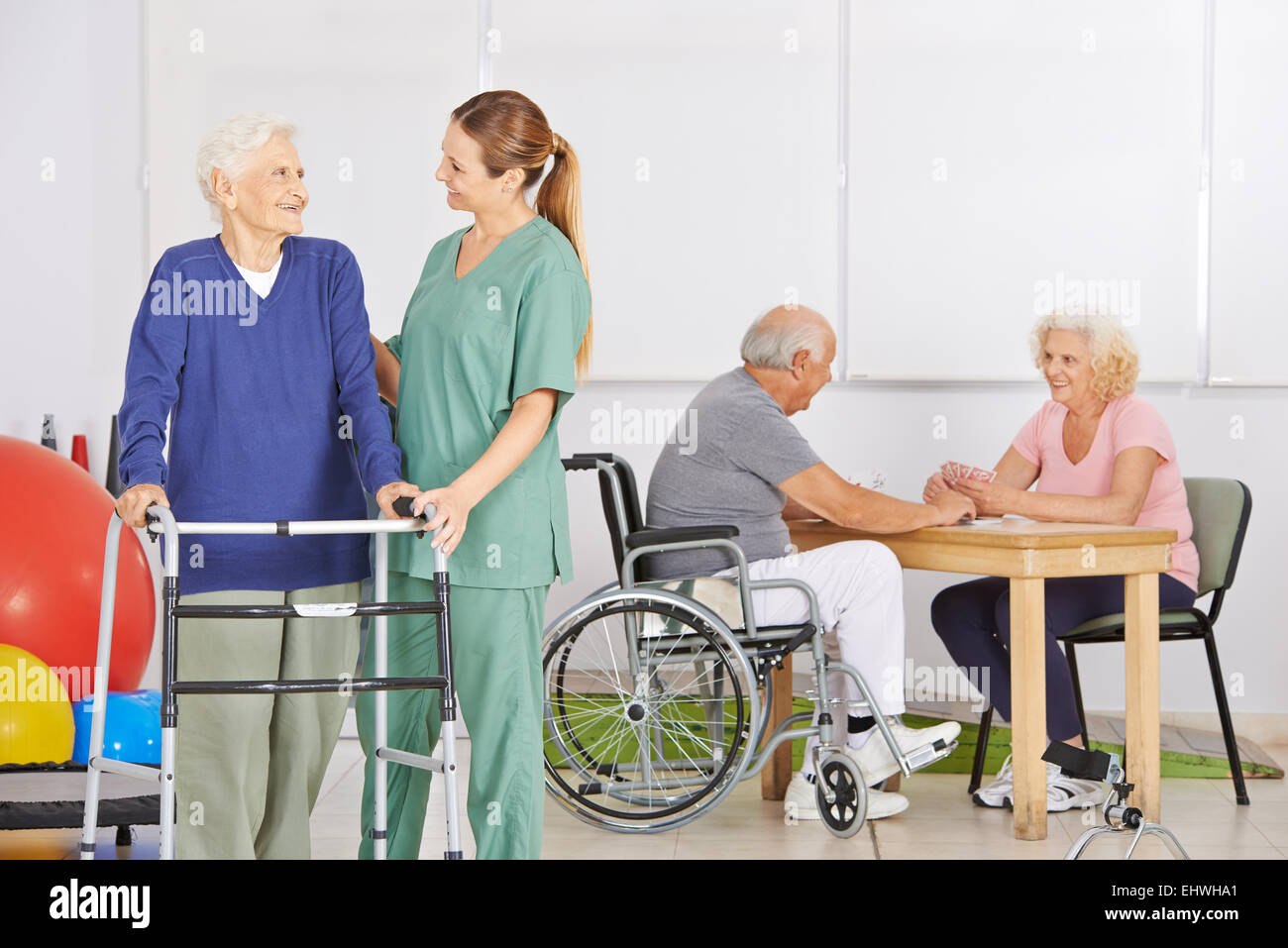 Sorridente infermiera geriatrica con gruppo di alti di persone in una casa di cura Foto Stock