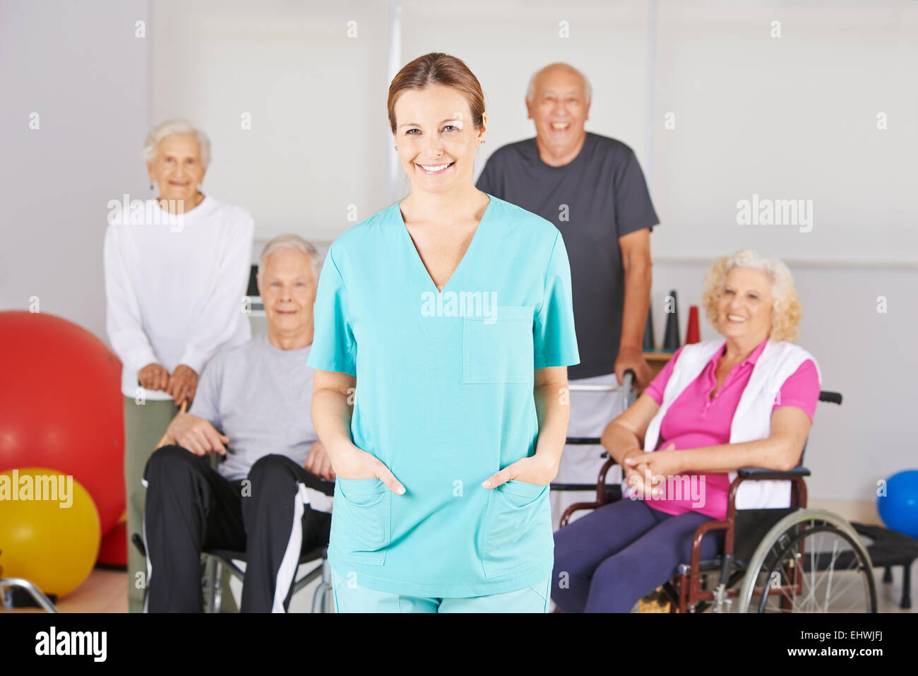 Sorridente infermiera geriatrica in piedi di fronte ad un buon gruppo di persone senior Foto Stock