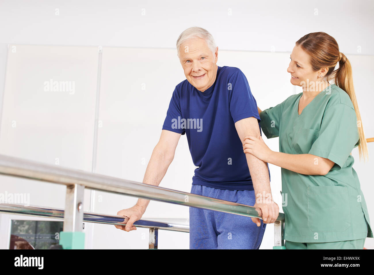 Il vecchio uomo in fisioterapia su tapis roulant con barre orizzontali e fisioterapista Foto Stock