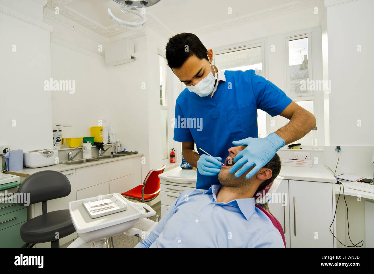 Dentista esaminare il paziente di sesso maschile Foto Stock