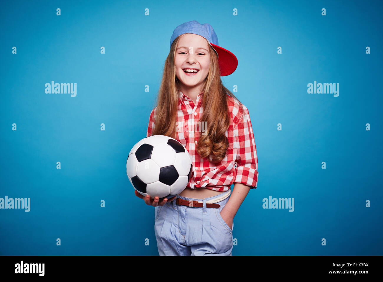 Ragazza sorridente mantenendo il pallone da calcio nelle sue mani Foto Stock