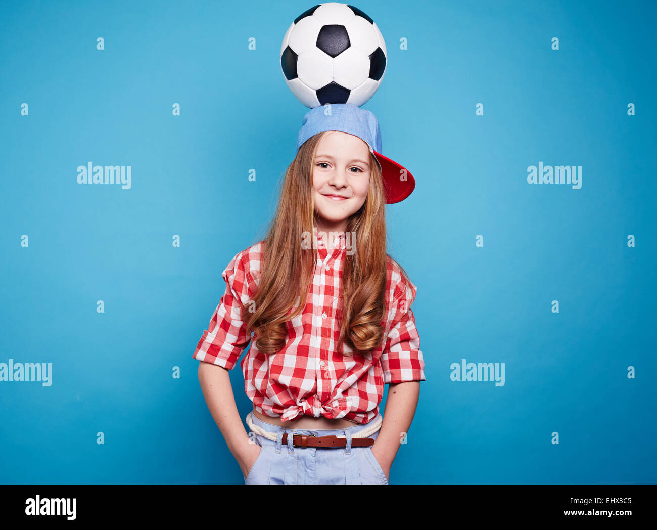 Sorridente ragazza con pallone da calcio sulla sua testa Foto Stock