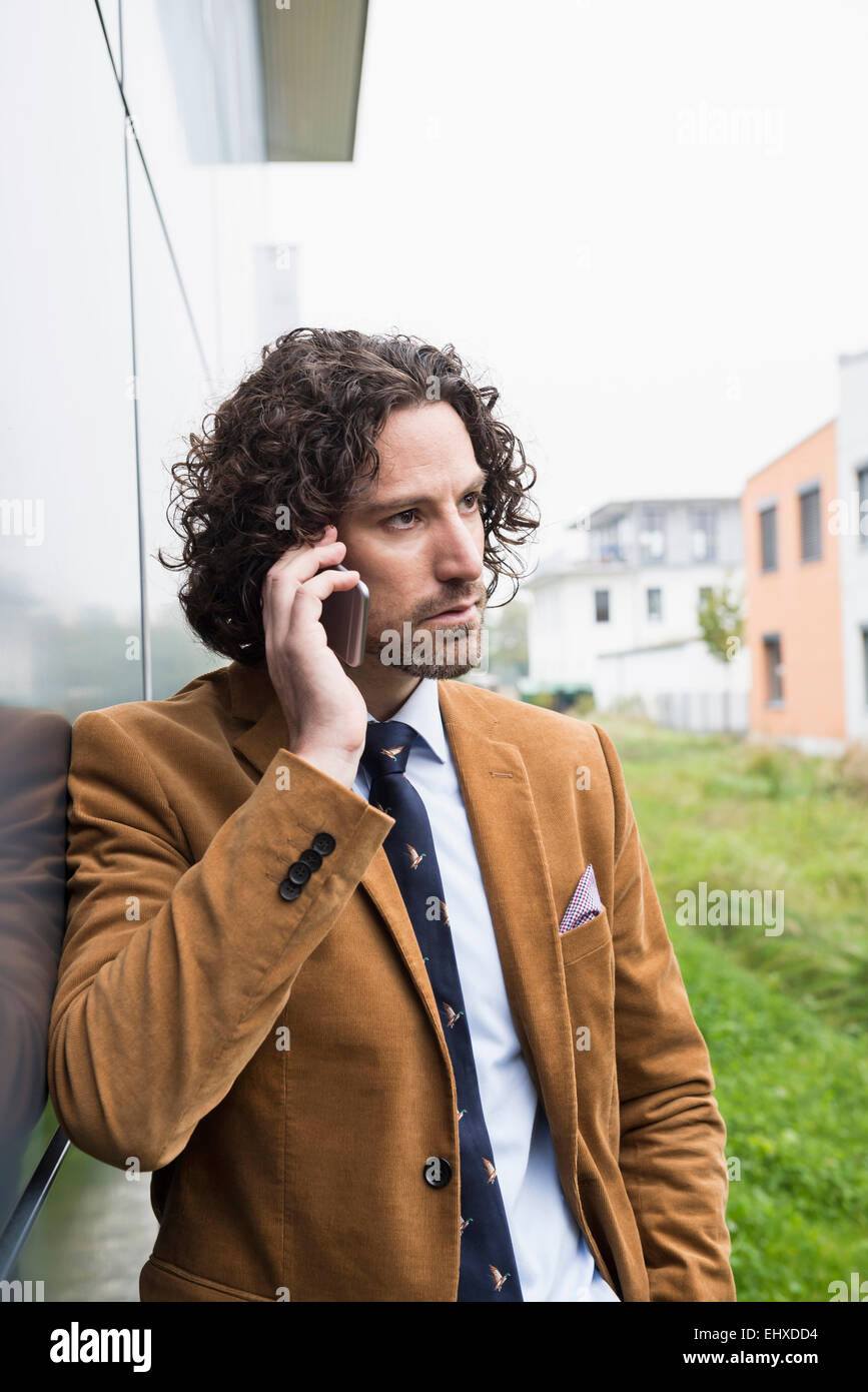 Ritratto giovane uomo capelli lunghi tuta telefono cellulare Foto Stock