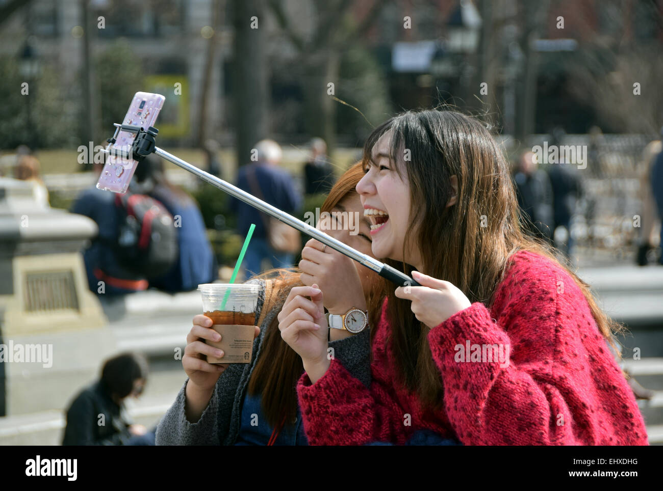 Due Asian ridere le donne che prendono un selfie vicino alla fontana di Washington Square Park nel Greenwich Village di New York City Foto Stock
