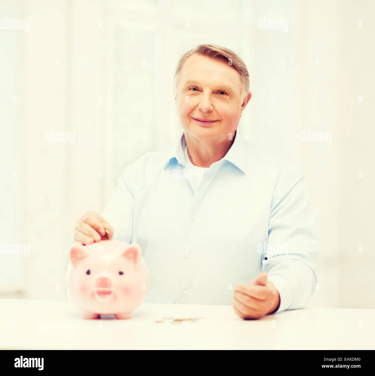 Il vecchio uomo di mettere moneta nella grande salvadanaio Foto Stock