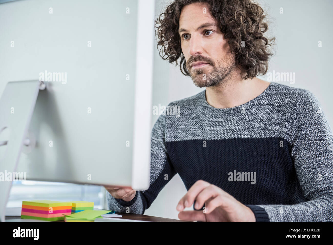 Imprenditore seduto alla scrivania che lavora sul computer in ufficio, Monaco di Baviera, Germania Foto Stock