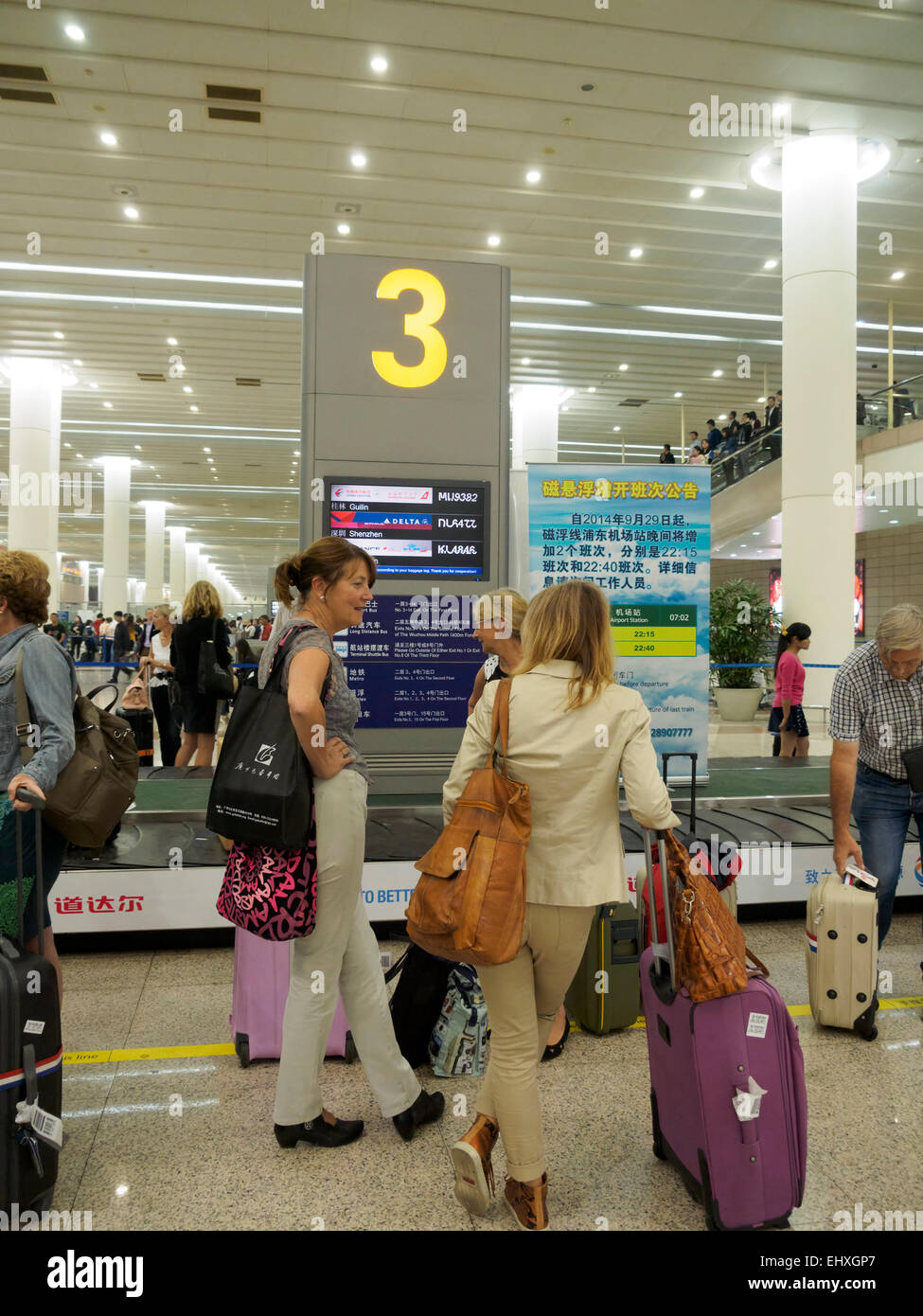 Persone in attesa per i bagagli presso il reclamo bagagli giostra all'aeroporto internazionale di Pudong di Shanghai, Cina Foto Stock