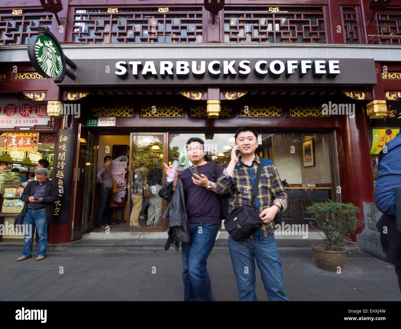 Due giovani cinesi uomini al di fuori di un Starbucks Coffee shop situato nel' Yuyuan Tourist Mart, Shanghai, Cina Foto Stock