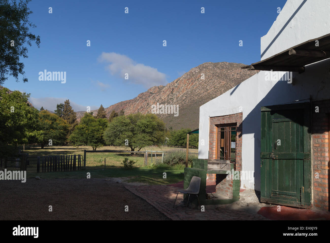 Un imbiancato vecchia fattoria sorge sotto una montagna in Montague, Sud Africa. Foto Stock