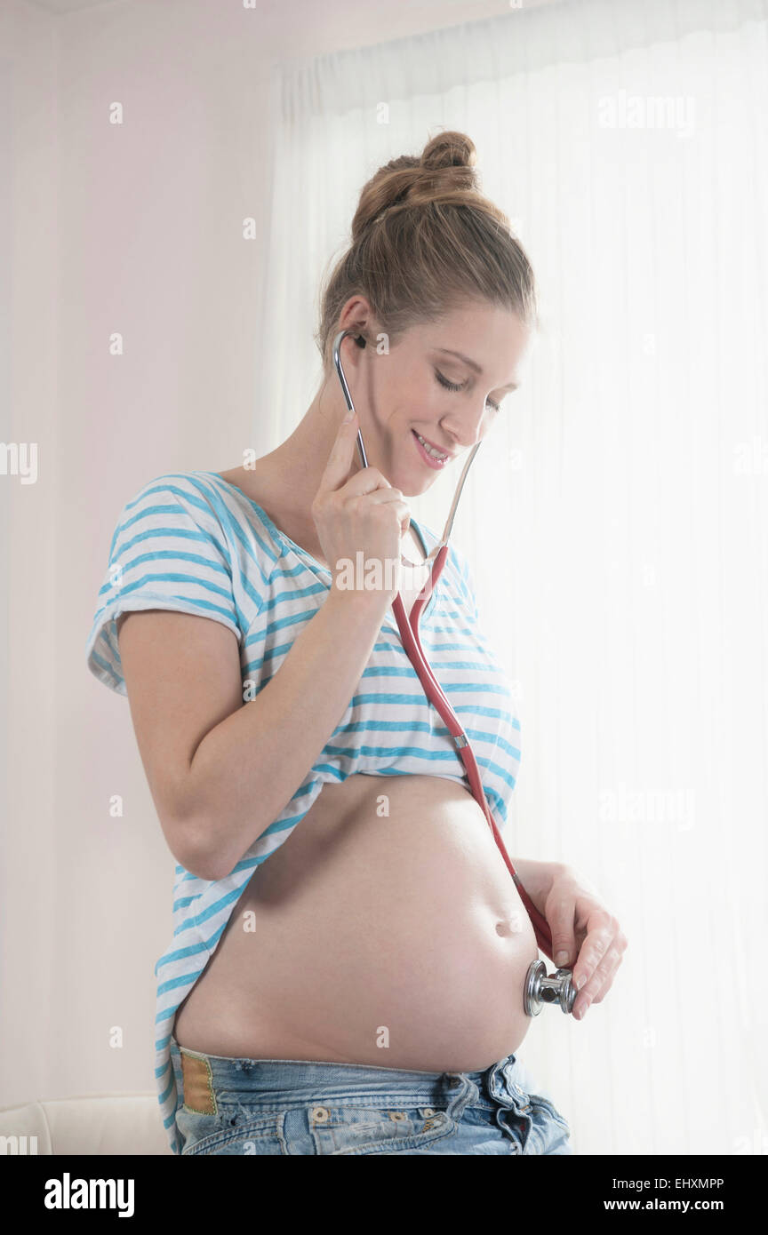 Donna incinta stetoscopio ascolto dello stomaco Foto Stock