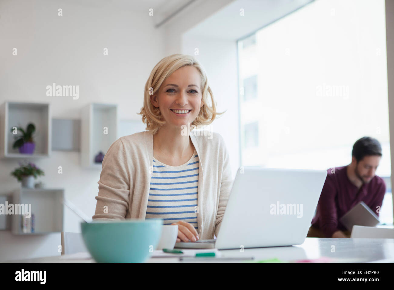 Ritratto di donna sorridente a lavorare con il computer portatile presso l'ufficio domestico Foto Stock