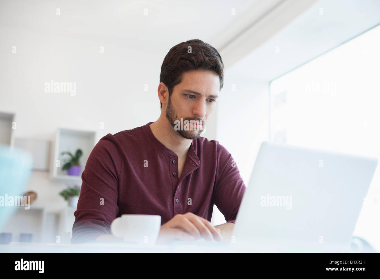 Ritratto di uomo che lavora con il computer portatile presso l'ufficio domestico Foto Stock