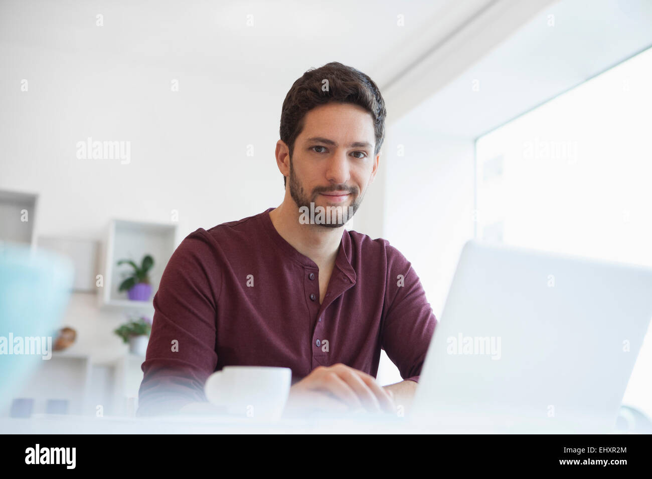 Ritratto di uomo che lavora con il computer portatile presso l'ufficio domestico Foto Stock