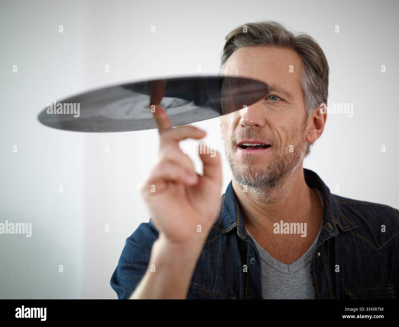 Uomo maturo scrutando il vecchio record di vinile Foto Stock