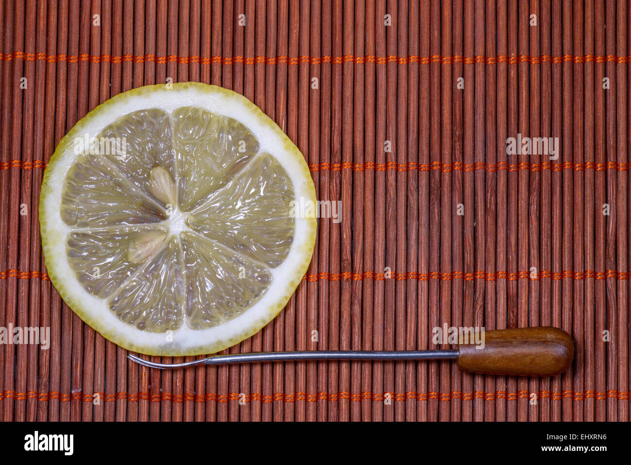 Fette di limone fresco con forche su un bel tappeto di vimini come sfondo Foto Stock