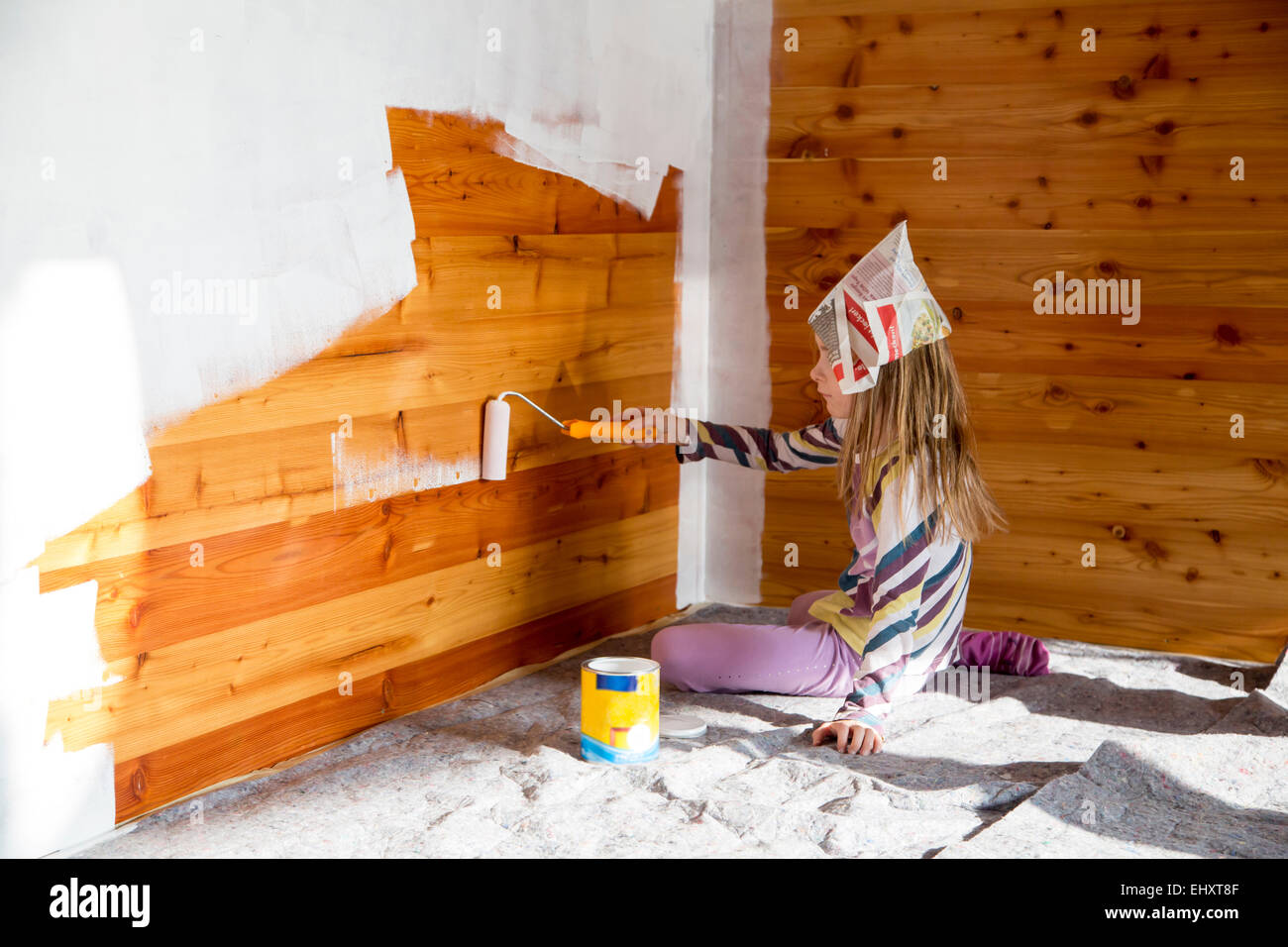 Ragazza pittura parete in legno con rullo di vernice Foto Stock