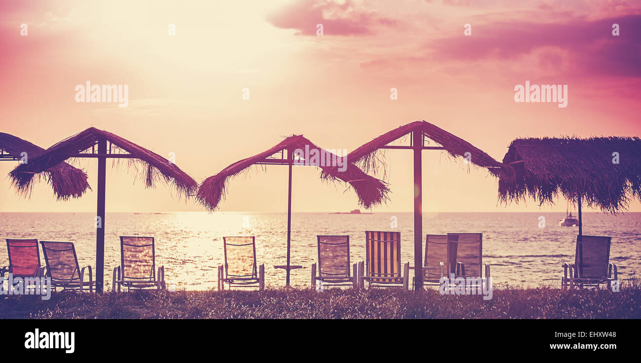 Retrò immagine filtrata di sedie a sdraio e ombrelloni al tramonto. Concetto per il riposo, il relax, vacanze. Foto Stock