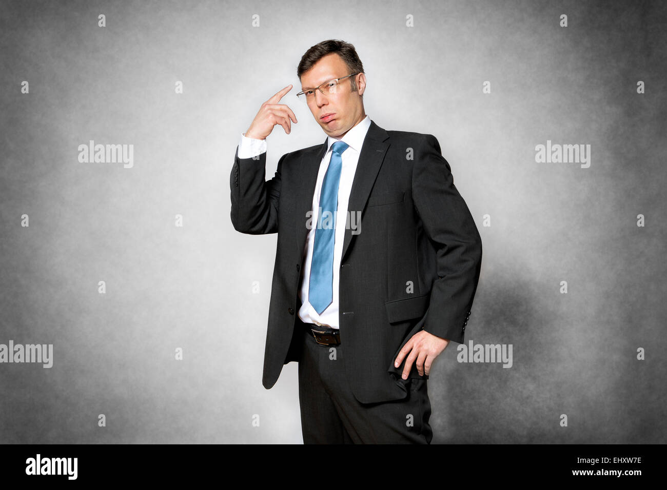 Immagine di presuntuoso business man in abito scuro puntando il dito a sua testa Foto Stock