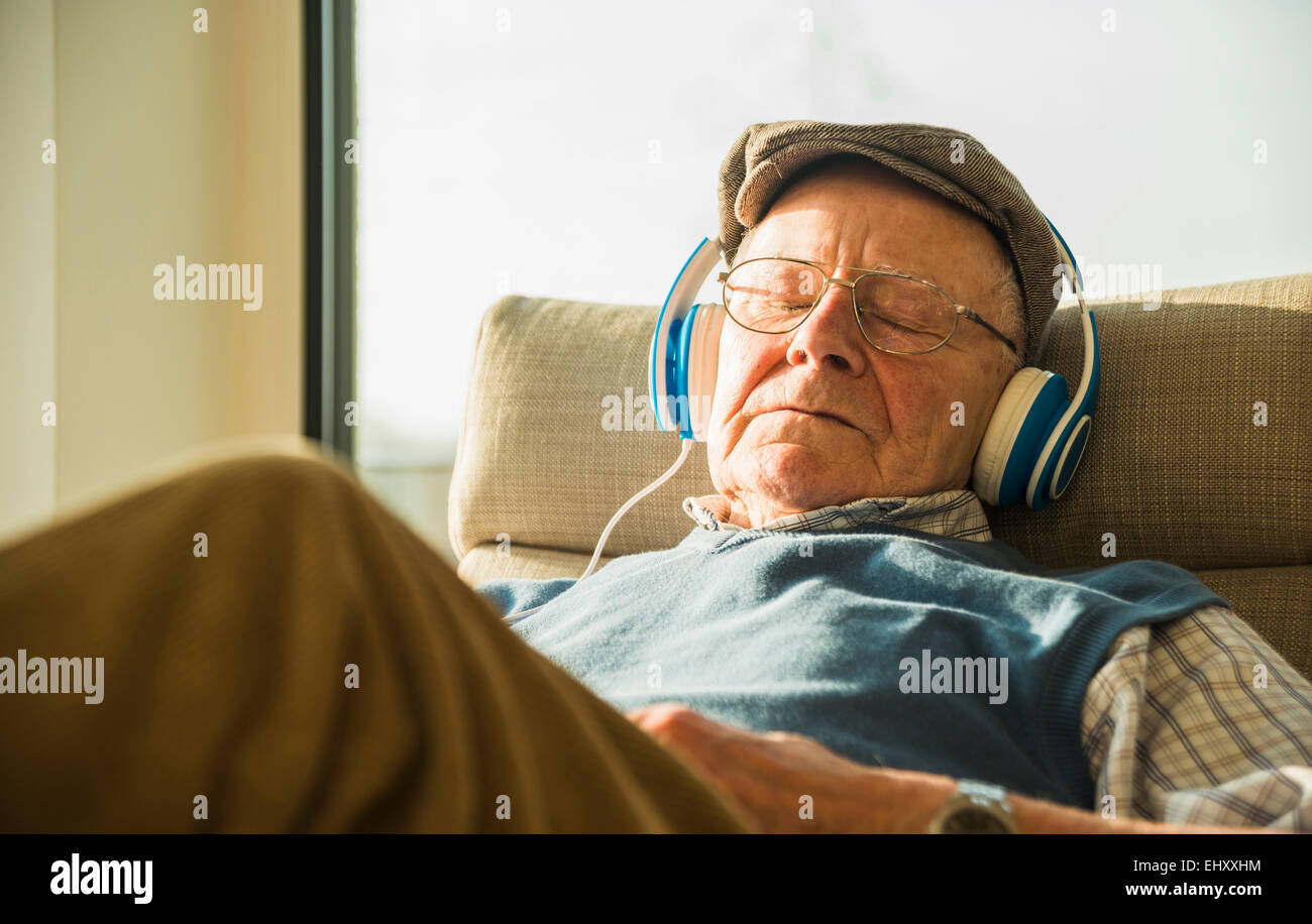 Senior uomo a casa rilassarsi con le cuffie Foto Stock