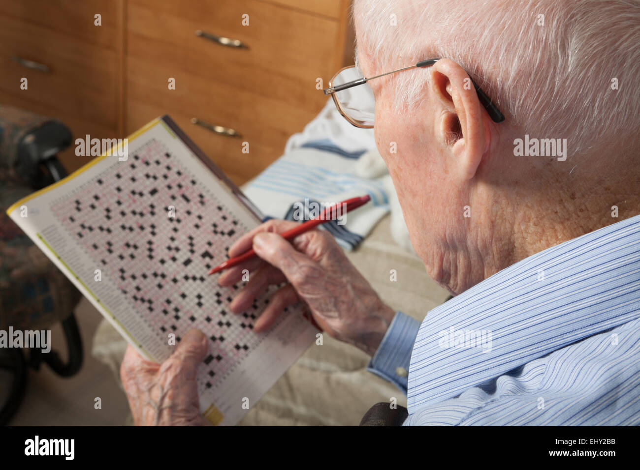 Un anziano uomo seduto facendo cruciverba hobby Foto Stock