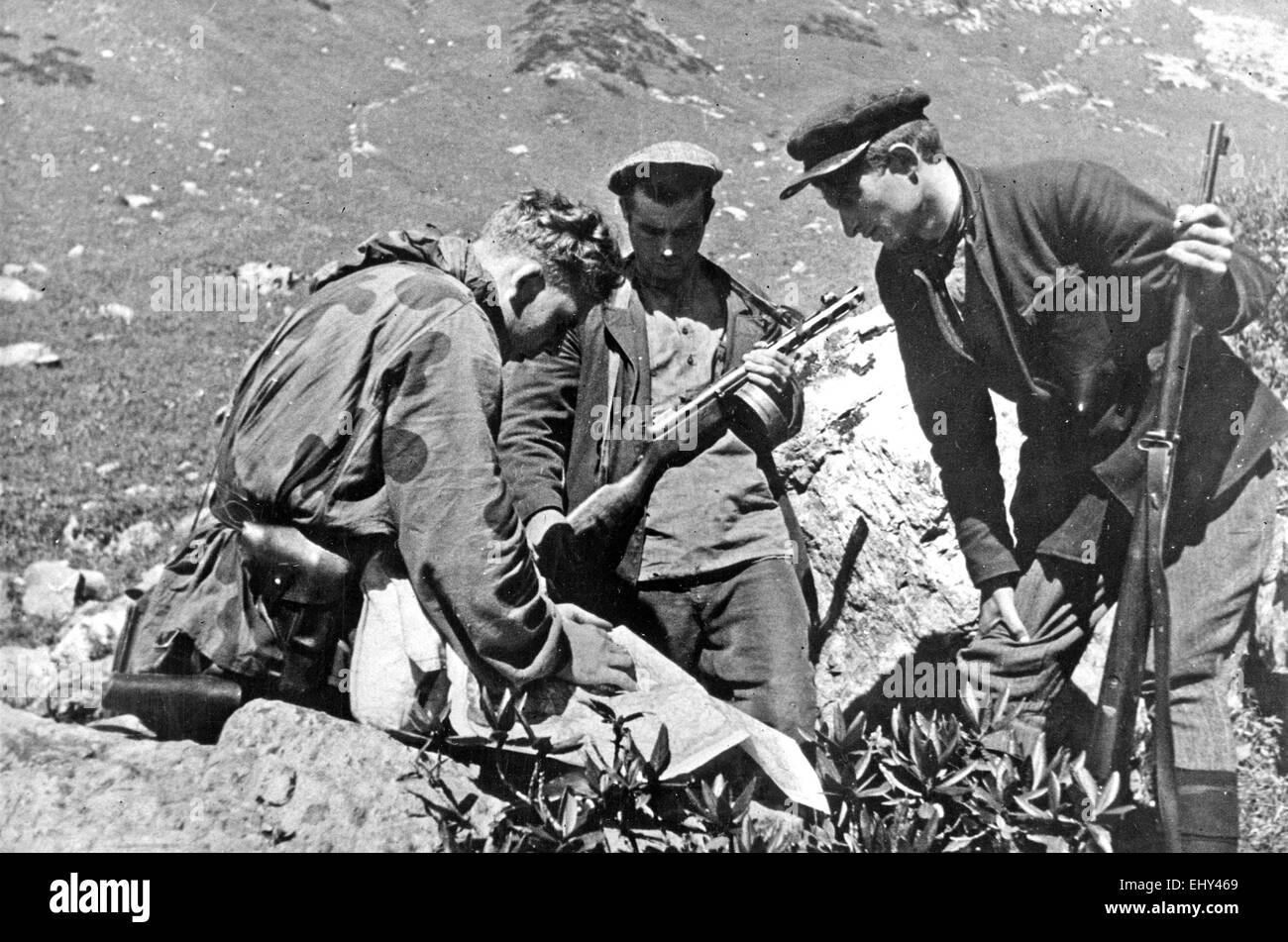 Cecchino sovietico consulta una mappa guardato dai partigiani locali nel Caucaso circa 1942 Foto Stock