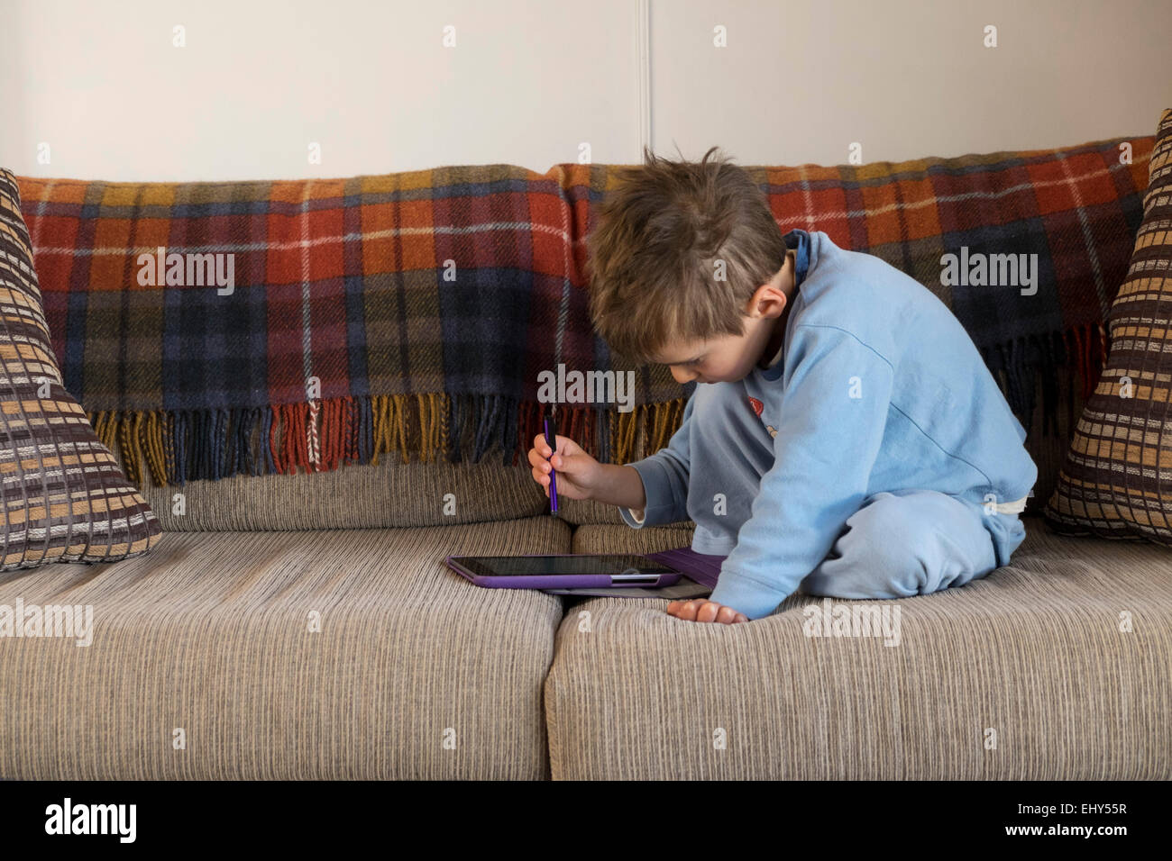 4 anno vecchio ragazzo giocando con tavoletta digitale sul divano Foto Stock