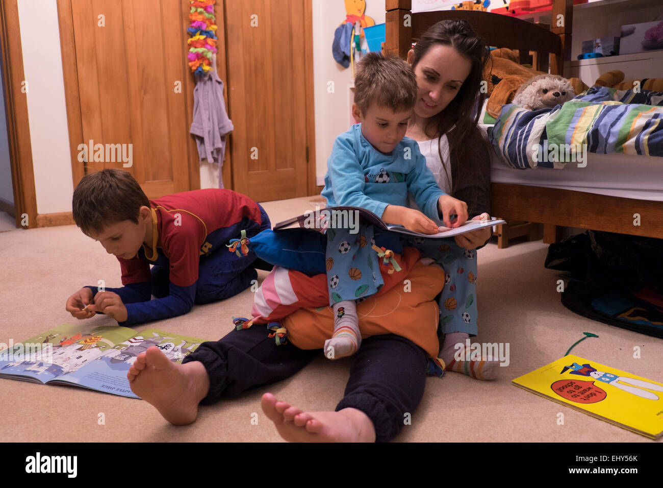 Lettura della ragazza per i bambini in camera da letto Foto Stock