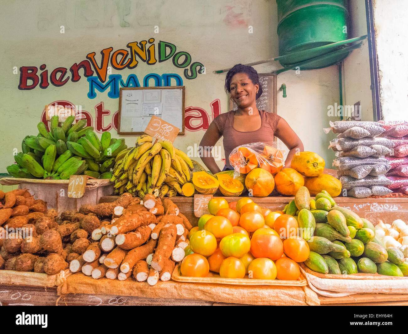 Una femmina di afro-cubane fornitore del mercato sta dietro la sua produzione di stand nella Habana Vieja, Cuba. Foto Stock