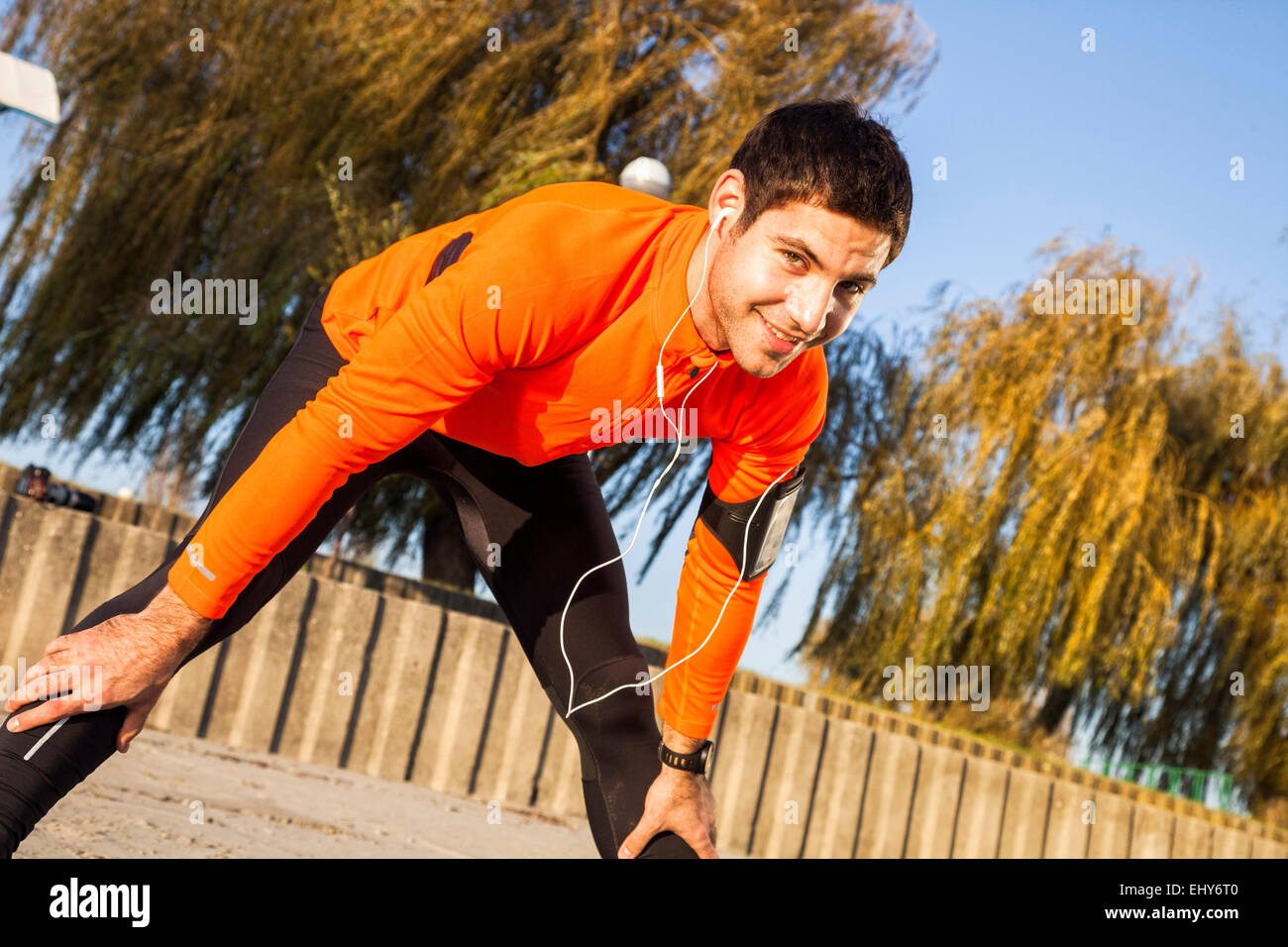 Runner maschio con le cuffie la piegatura su Foto Stock