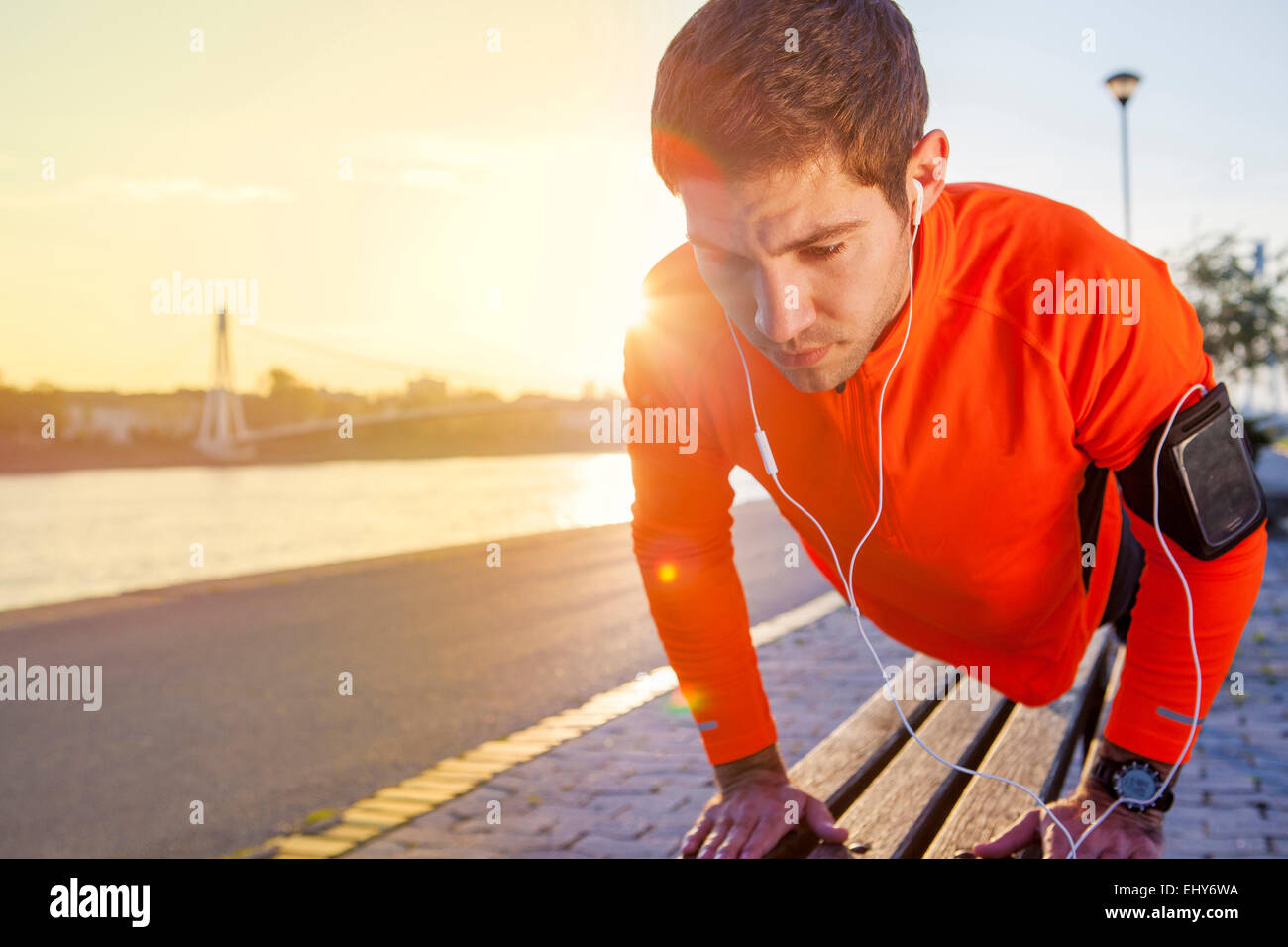 Runner maschio facendo push-up al tramonto Foto Stock