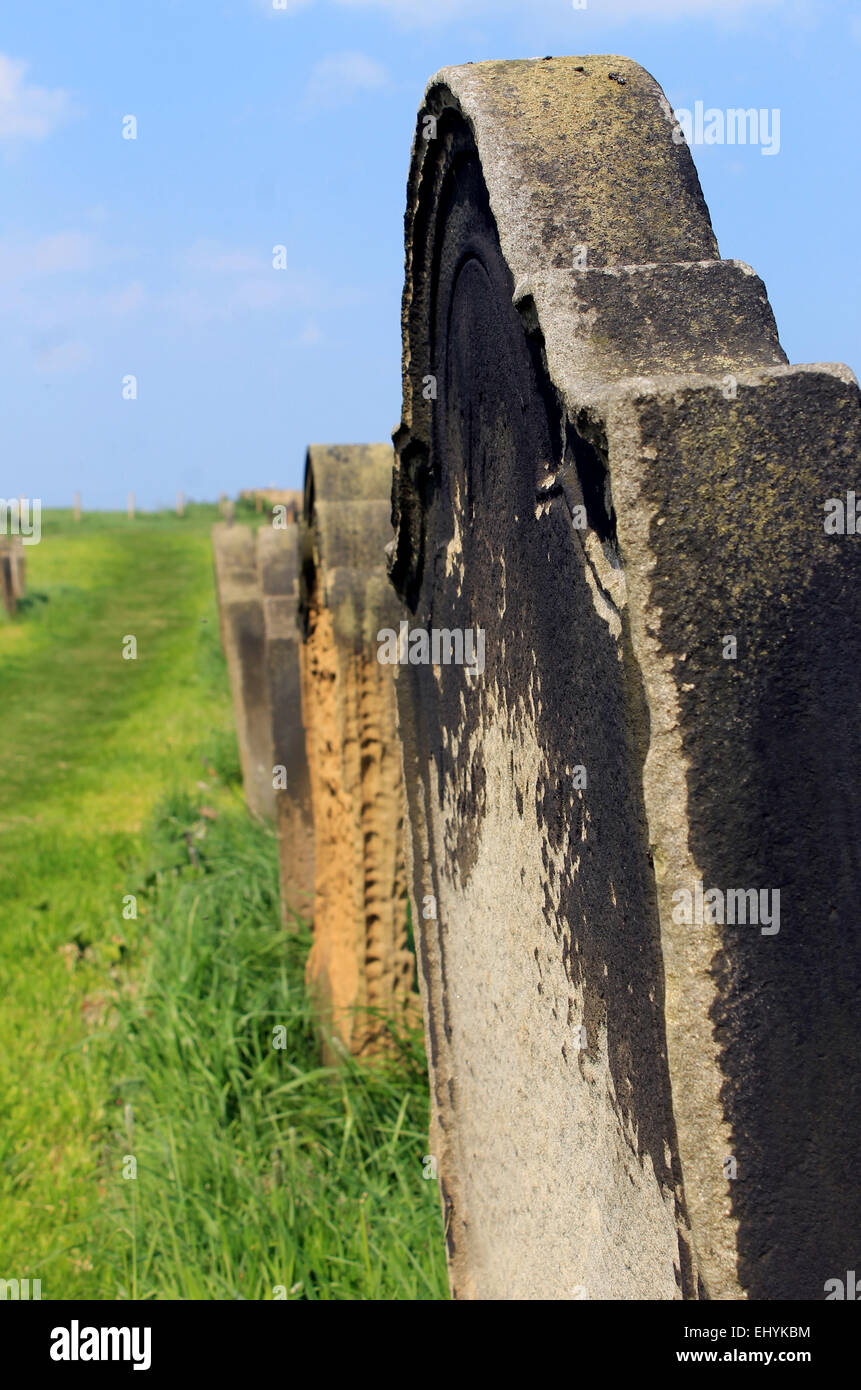 Vista panoramica di vecchie lapidi in un cimitero rurale con il focus sulla pietra in primo piano. Foto Stock
