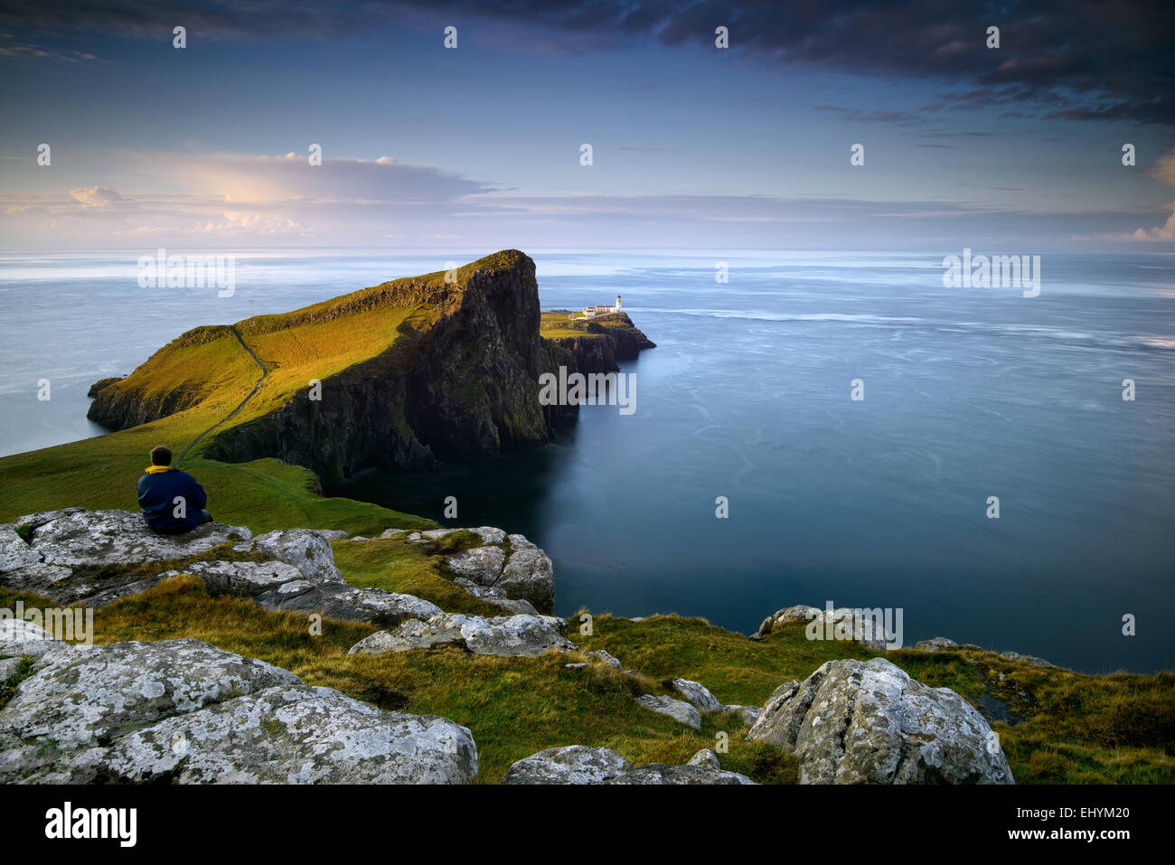 Metà uomo adulto seduto su una roccia che guarda al mare a Neist Point, Scozia Foto Stock