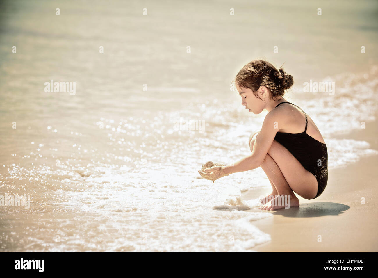 Ragazza che gioca con la sabbia sulla spiaggia, Messico Foto Stock