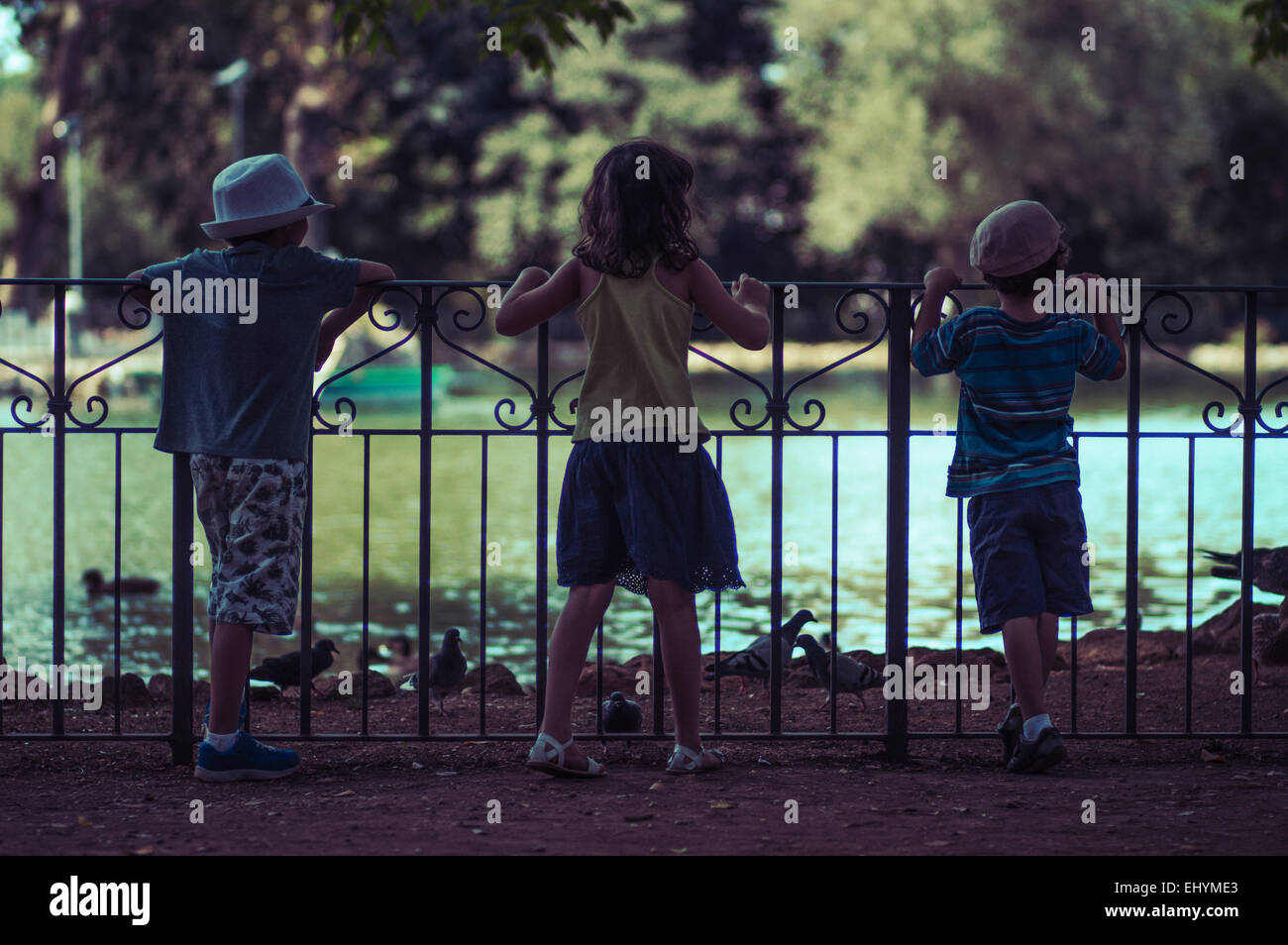 Tre bambini guardando le anatre su un lago, Italia Foto Stock