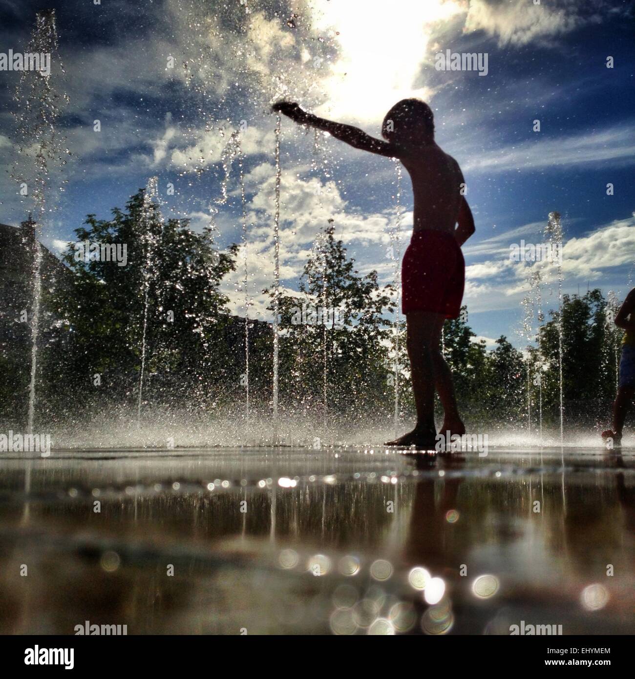 Silhouette di un ragazzo in piedi di una fontana di acqua, Niort, Francia Foto Stock